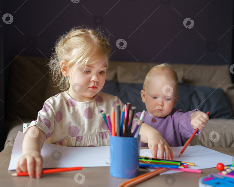 Скачать Двое детей, сестра и маленький брат, вместе рисуют карандашами дома фотосток Ozero