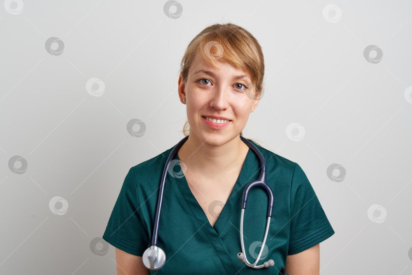 Скачать Улыбающаяся молодая медсестра-ассистент с фонендоскопом в зеленой униформе. Хирург скорой помощи фотосток Ozero