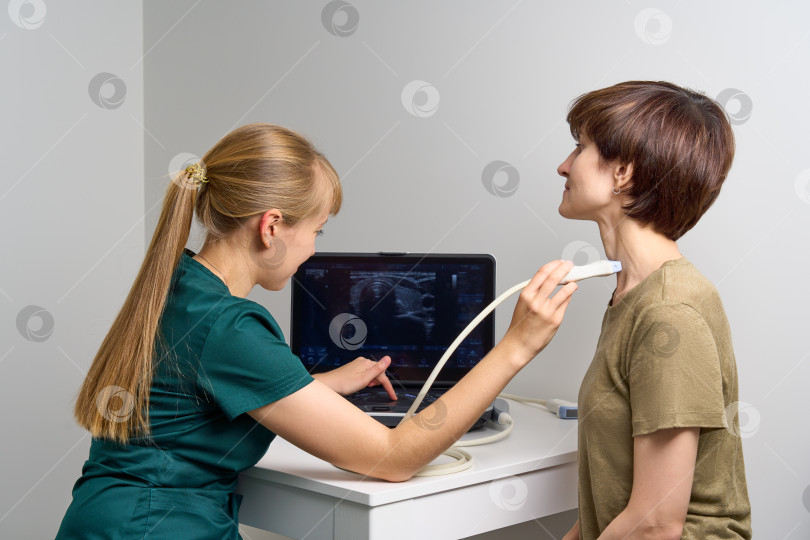 Скачать Женщина-сонографист осматривает горло. Медицинский работник, проводящий ультразвуковую диагностику фотосток Ozero