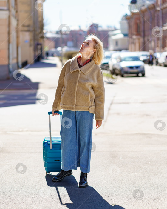 Скачать Пожилая женщина 60-ти лет с синим чемоданом, путешествующая одна после выхода на пенсию фотосток Ozero