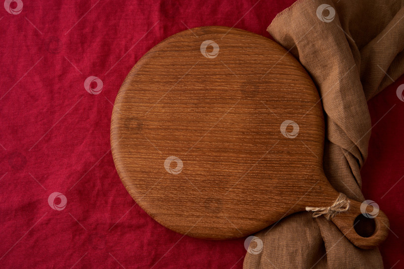 Скачать Разместите на столе. Макет кулинарного фона с круглой деревянной разделочной доской на льняной ткани ярко-красного клюквенного цвета фотосток Ozero