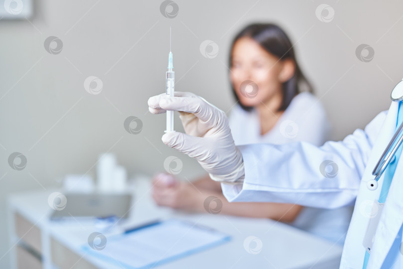 Скачать Врач держит в руках шприц с вакциной от коронавируса covid 19, готовый сделать прививку счастливой африканской пациентке фотосток Ozero