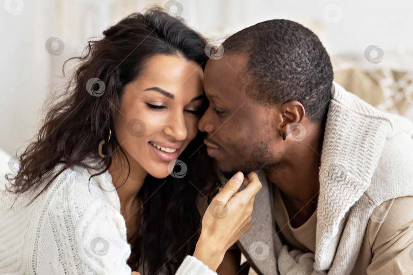 Скачать Влюбленная пара - чернокожий мужчина и мулатка на кровати в светлой комнате. Разнообразная семья фотосток Ozero