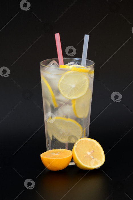Скачать Освежающий лимонад в высоком граненом стакане с трубочками для льда и ломтиками спелого лимона. фотосток Ozero