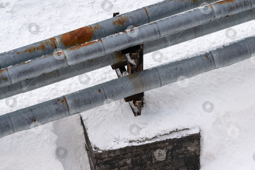 Скачать Наружные городские трубы центрального отопления с ржавыми теплоизоляционными оболочками, покрытыми снегом после снегопада фотосток Ozero