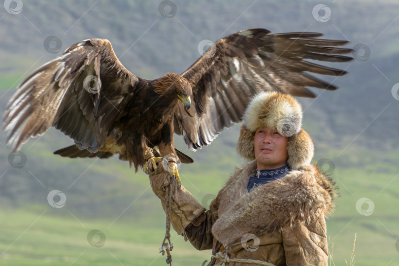 Скачать Горный орел сидит на руке киргизского мужчины. фотосток Ozero