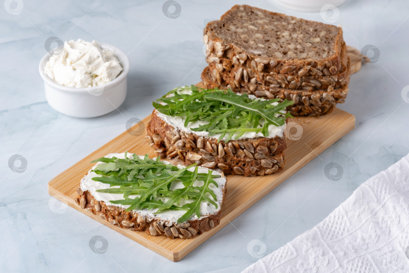Скачать Бутерброды с творожным сыром и рукколой. Ржаной хлеб с семечками фотосток Ozero