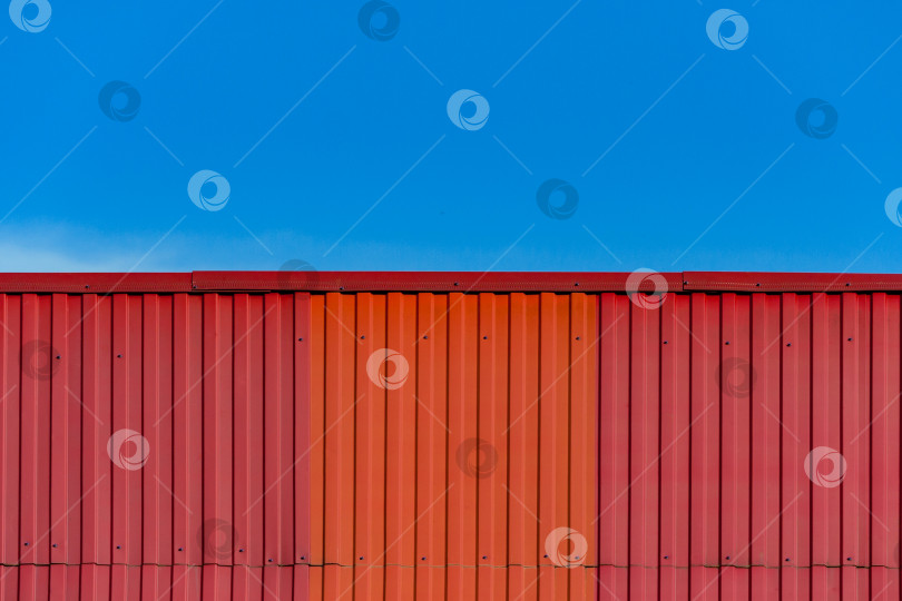 Скачать Фрагмент красно оранжевой металлочерепичной крыши на фоне яркосинего неба фотосток Ozero