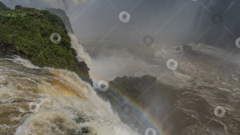 Скачать Пенящиеся струи водопада низвергаются в реку со скалы. фотосток Ozero