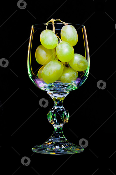 Скачать Бокал для вина, наполненный виноградной веточкой на черном фоне (концепция) фотосток Ozero