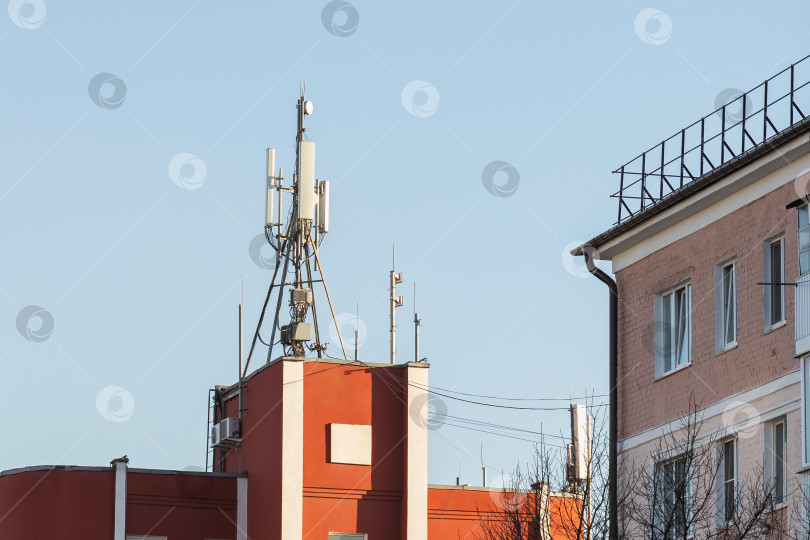 Скачать Вышки сотовой связи на крыше здания рядом с жилыми домами, концепция на тему опасного воздействия радиоволн на здоровье человека фотосток Ozero