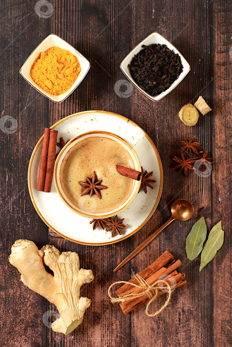 Скачать Индийский масала-чай с молоком, имбирем, анисом и корицей на старинном деревянном столе. Традиционный напиток со специями, концепция кафе, реклама ресторана и меню. фотосток Ozero