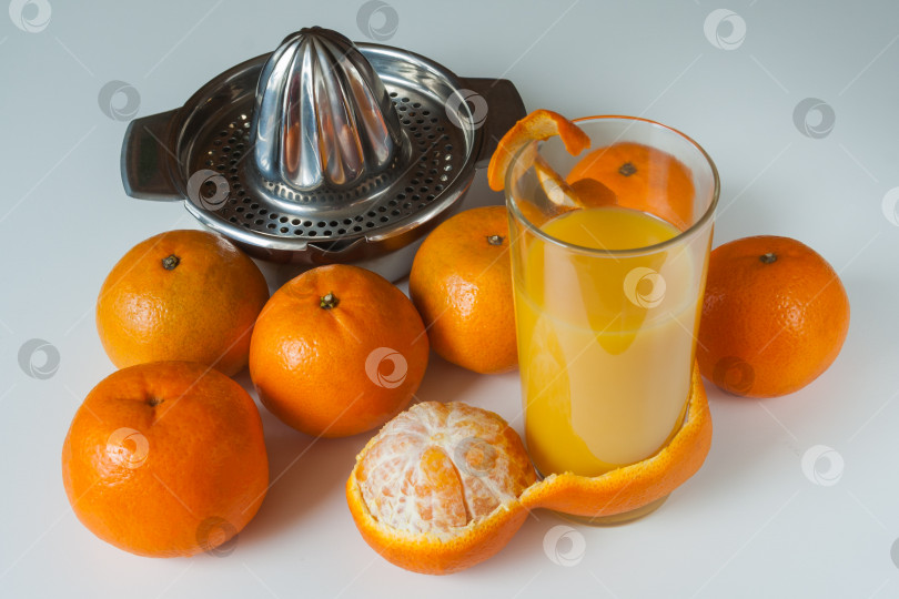 Скачать Стакан полезного свежевыжатого сока из мандаринов и ручная соковыжималка на белом фоне фотосток Ozero