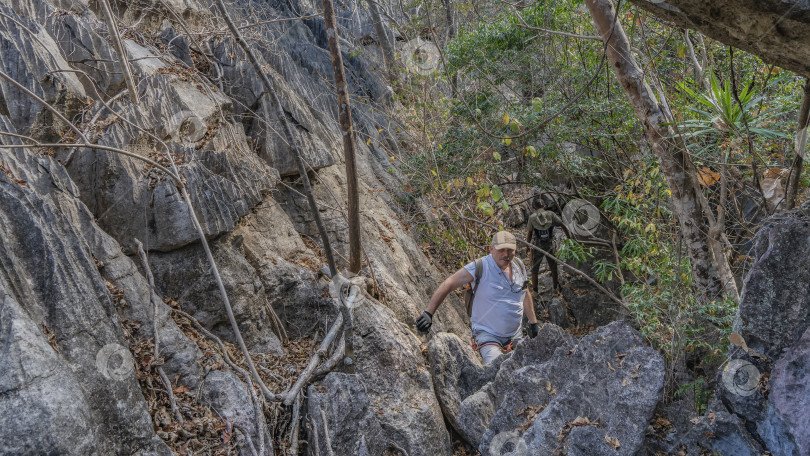 Скачать Мужчина с рюкзаком и защитным снаряжением взбирается на скалу. фотосток Ozero
