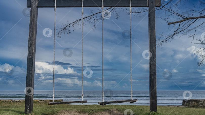 Скачать Качели подвешены на веревках к деревянной перекладине на пляже. фотосток Ozero