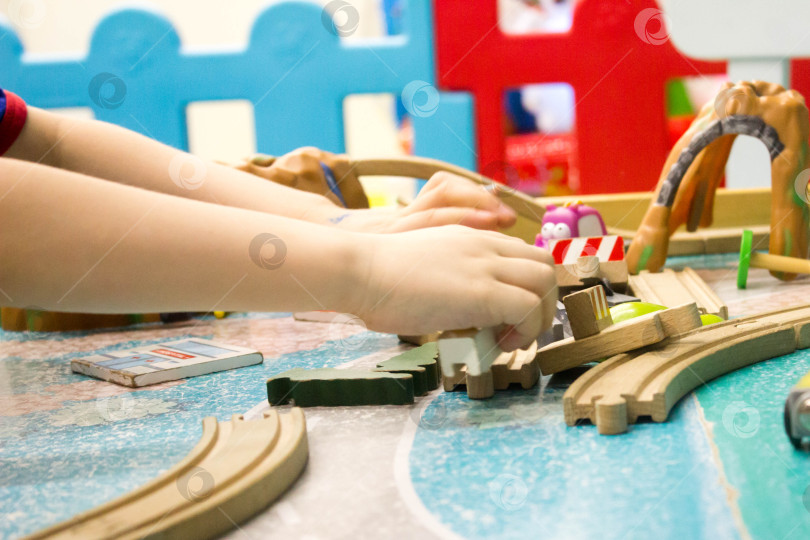 Скачать Крупный план детских рук, играющих с деревянным поездом фотосток Ozero