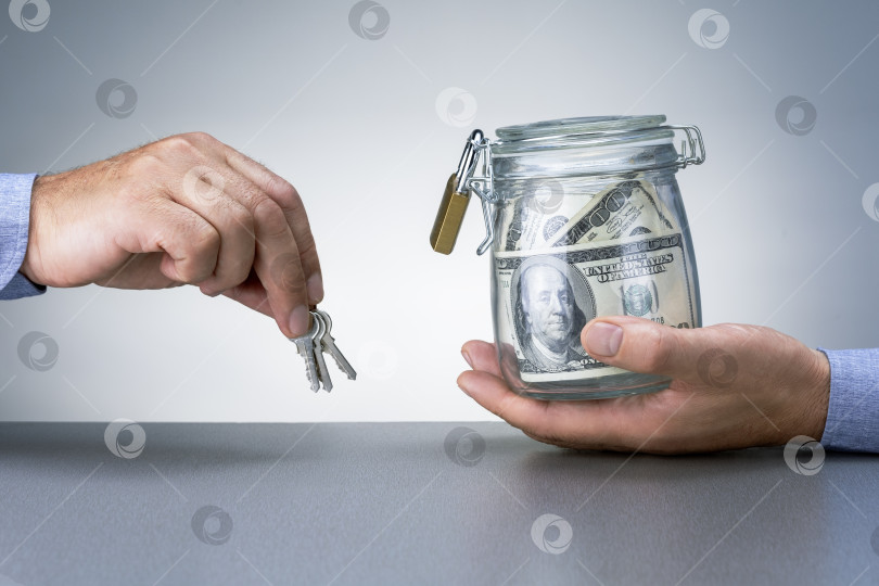 Скачать Передающий деньги в банк. Мужчина держит ключи от сейфа с долларовыми банкнотами. фотосток Ozero