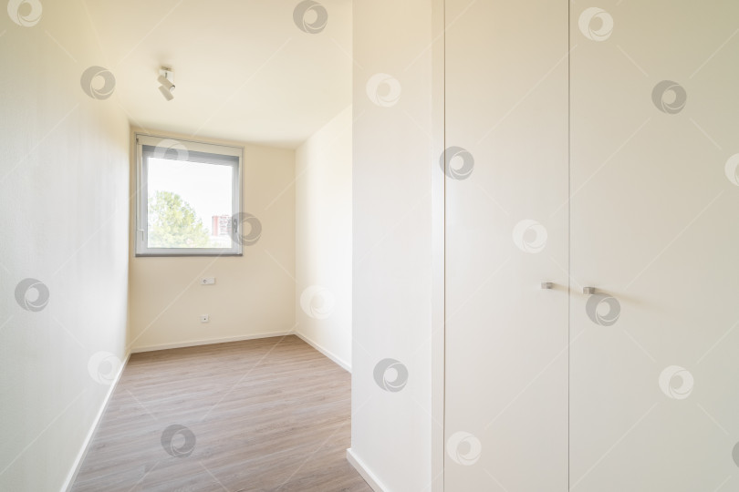 Скачать Пустая маленькая светлая спальня со встроенным белым шкафом фотосток Ozero