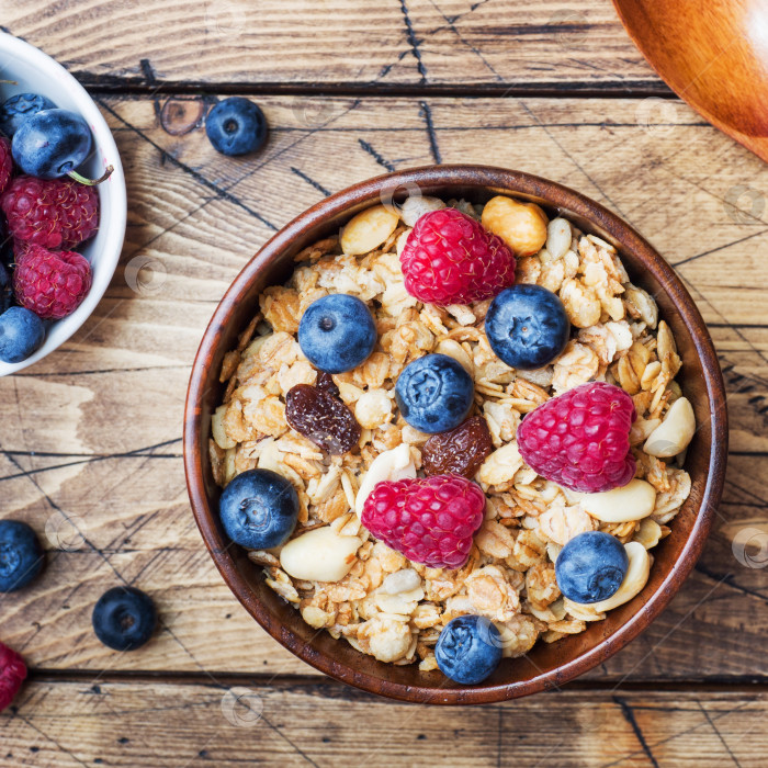 Скачать Полезный завтрак. Свежая гранола, мюсли с йогуртом и ягодами на деревянном фоне. фотосток Ozero