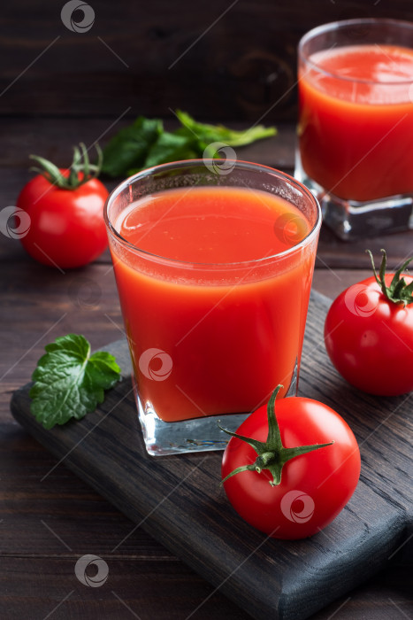 Скачать Томатный сок в стеклянных бокалах и свежие спелые помидоры на ветке. Фон из темного дерева с пространством для копирования. фотосток Ozero