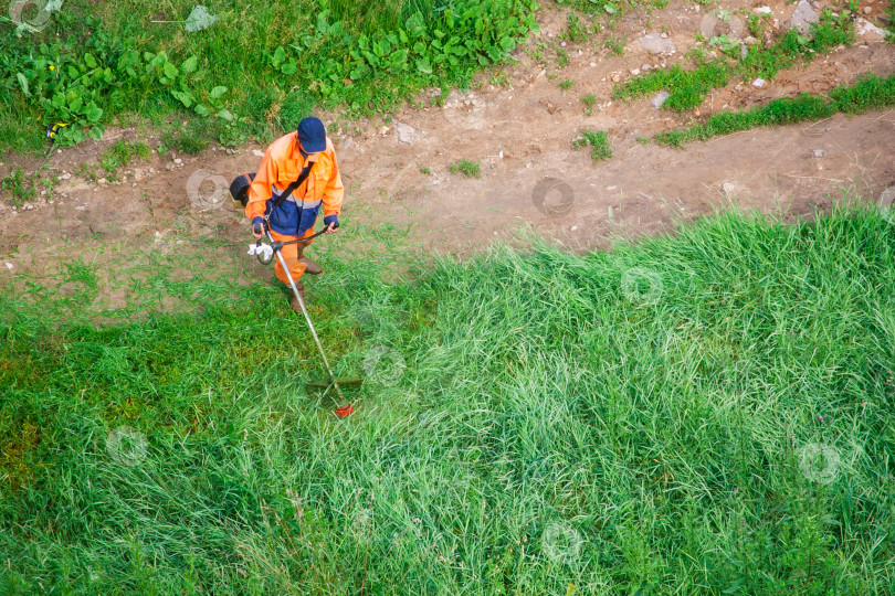 Скачать Мужчина косит высокую траву триммером фотосток Ozero
