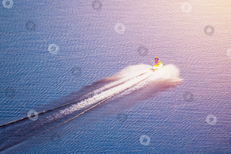 Скачать Водный велосипед (плавсредство) плывет по воде, освещенной солнечным светом фотосток Ozero