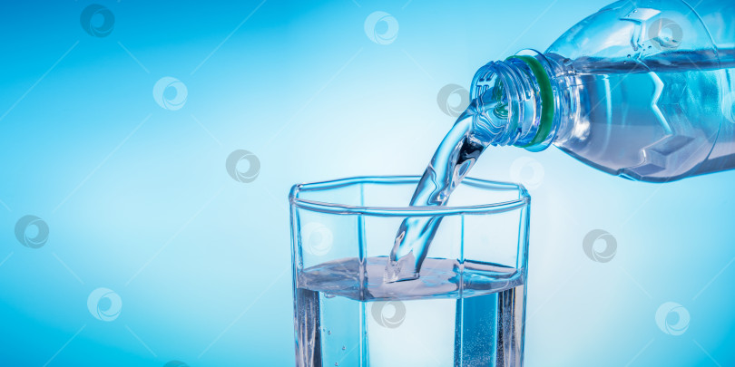 Скачать Наливание воды из бутылки в стакан на синем фоне. фотосток Ozero