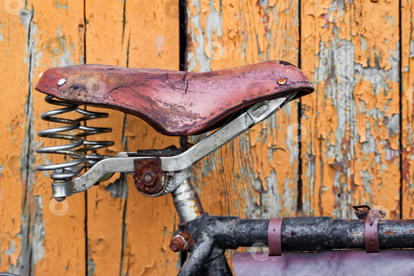 Скачать Старое велосипедное сиденье на фоне крашеных деревянных досок фотосток Ozero
