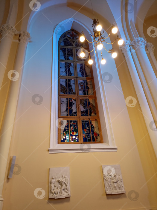 Скачать Окно с витражами и горящая люстра в католическом соборе фотосток Ozero