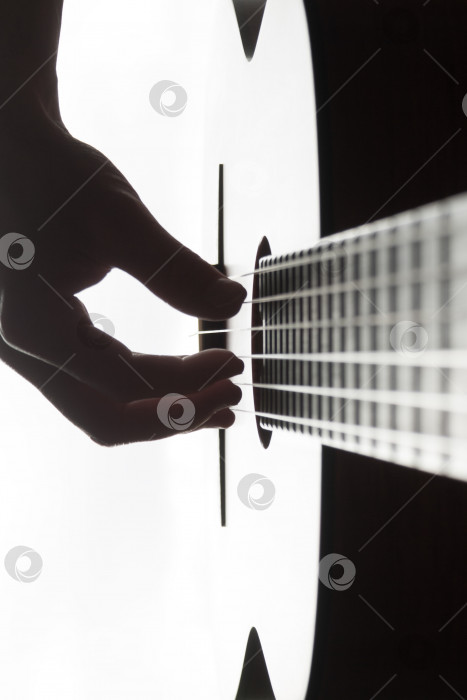 Скачать Мужская рука, играющая на классической гитаре на фоне дневного света фотосток Ozero