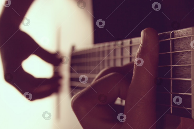 Скачать Мужские руки, играющие на классической гитаре на фоне белого света (тонированный) фотосток Ozero