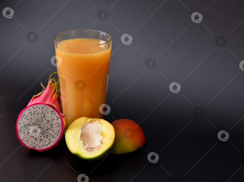 Скачать Пейте сок в высоком граненом стакане на черном фоне, рядом со спелыми фруктами. фотосток Ozero