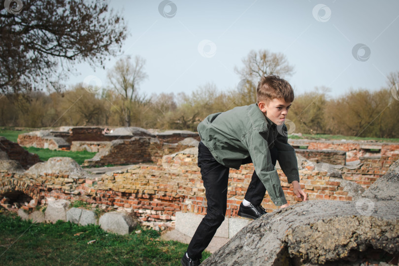 Скачать Маленький мальчик гуляет по парку рядом со старой крепостью фотосток Ozero