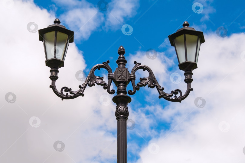 Скачать Две лампы на кованом металлическом фонаре в стиле ретро на фоне неба фотосток Ozero