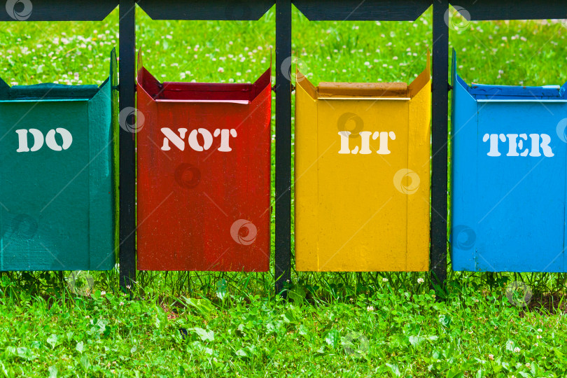 Скачать Четырехцветный мусорный бак в парке с надписью "не мусорить" фотосток Ozero