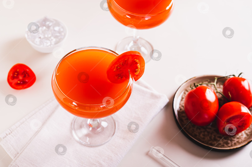 Скачать Оригинальный коктейль с томатным мартини в бокалах и помидорами на тарелке на столе фотосток Ozero