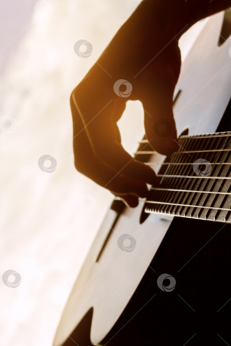 Скачать Рука мужчины, играющего на классической гитаре на фоне дневного света фотосток Ozero