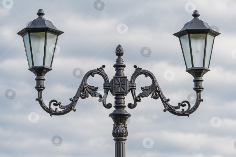 Скачать Две лампы на кованом металлическом фонарном столбе в стиле ретро на фоне пасмурного неба фотосток Ozero