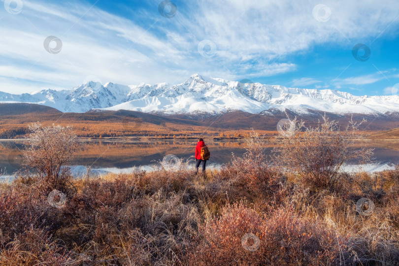 Скачать Вид сзади на путешественника в красном, смотрящего на горное озеро фотосток Ozero