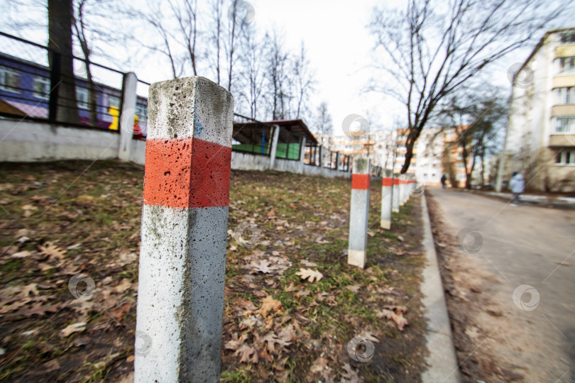 Скачать Ряд бетонных столбов в красную и белую полоску на асфальтированной дороге фотосток Ozero