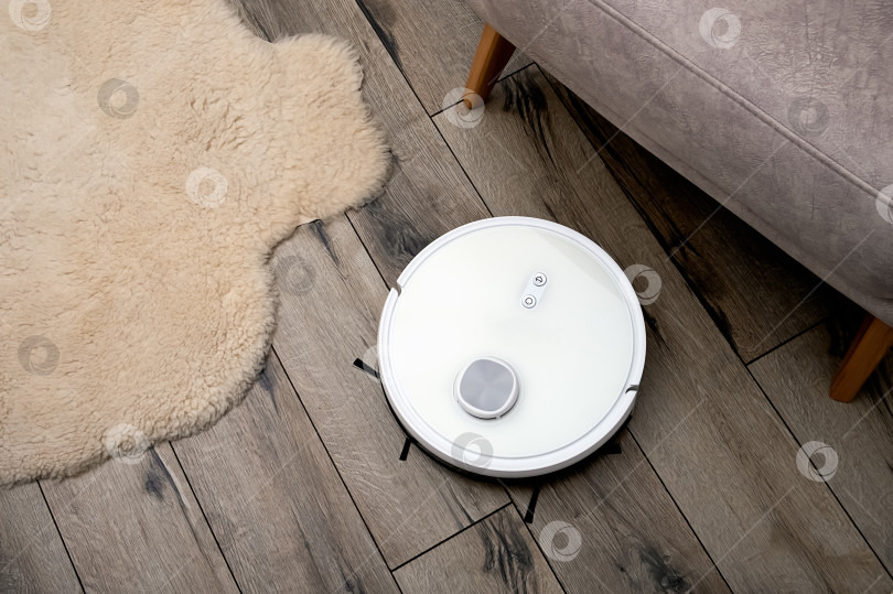 Скачать Робот-пылесос на деревянном полу в современном интерьере. Выборочный фокус. фотосток Ozero