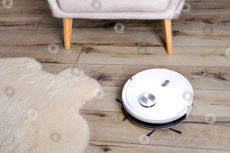 Скачать Робот-пылесос на деревянном полу в современном интерьере. Выборочный фокус. фотосток Ozero