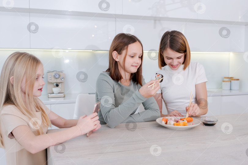 Скачать Три девушки сидят за столом и едят суши фотосток Ozero