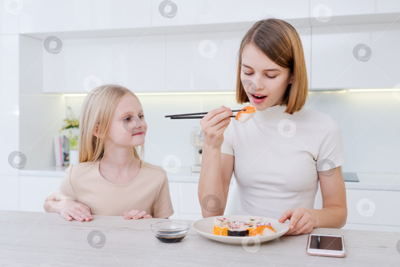 Скачать Женщина и маленькая девочка едят суши на кухне фотосток Ozero
