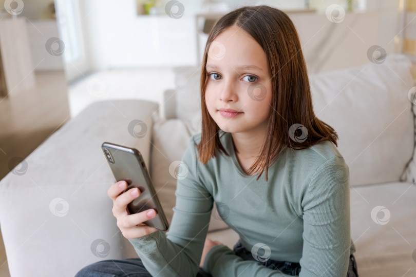 Скачать Девушка сидит на диване с мобильным телефоном в руках фотосток Ozero
