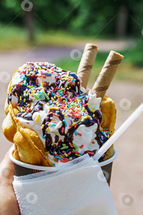 Скачать Мороженое с вафлями, шоколадной посыпкой и разноцветной глазурью в руках фотосток Ozero