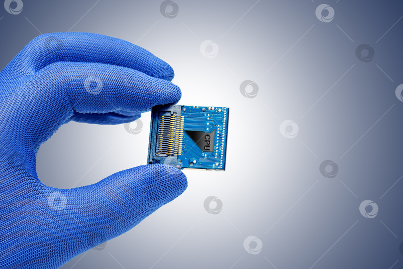 Скачать рука держит центральный процессор на серо-голубом фоне.  Концепция производства или ремонта электронных микросхем, компьютерных систем фотосток Ozero