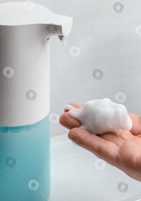 Скачать Автоматический дозатор мыла в ванной. Рука с мыльным раствором крупным планом. фотосток Ozero