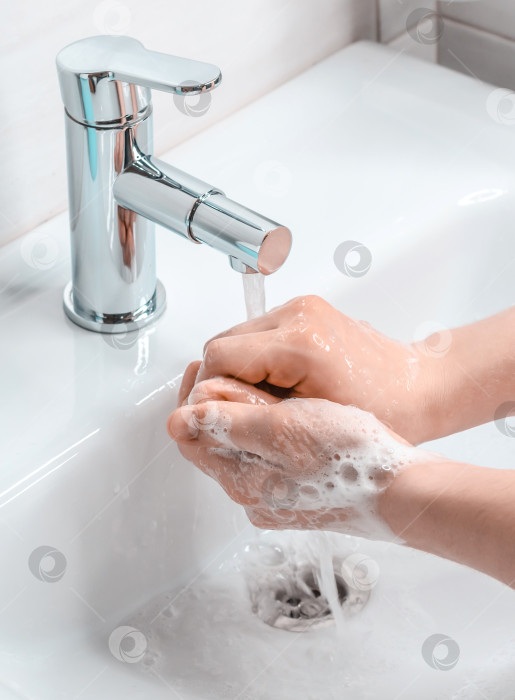 Скачать Мытье рук с мылом в ванной. Молодой парень моет руки с мылом. Борьба с коронавирусом. фотосток Ozero