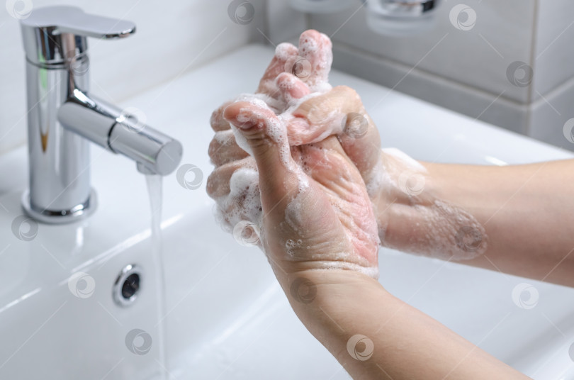 Скачать Мытье рук с мылом. Профилактические меры против заражения. Молодой парень моет руки с мылом в ванной. Гигиена тела. Борьба с COVID-19. фотосток Ozero